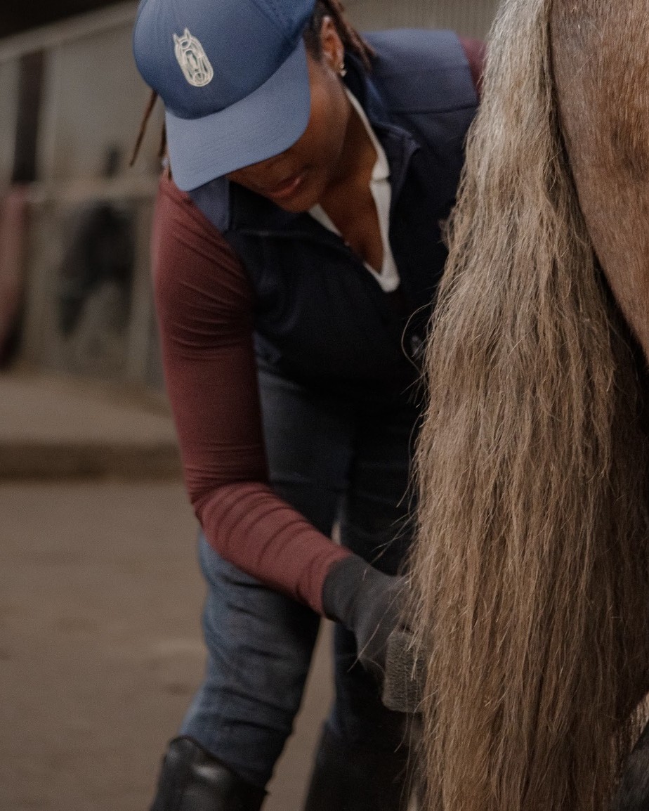 A groom working at a horse's tail